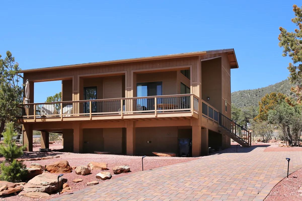 A wooden deck overlooks the surrounding forest, with large windows framing the view. The space invites relaxation and gathering after a hike, with the natural landscape front and center.