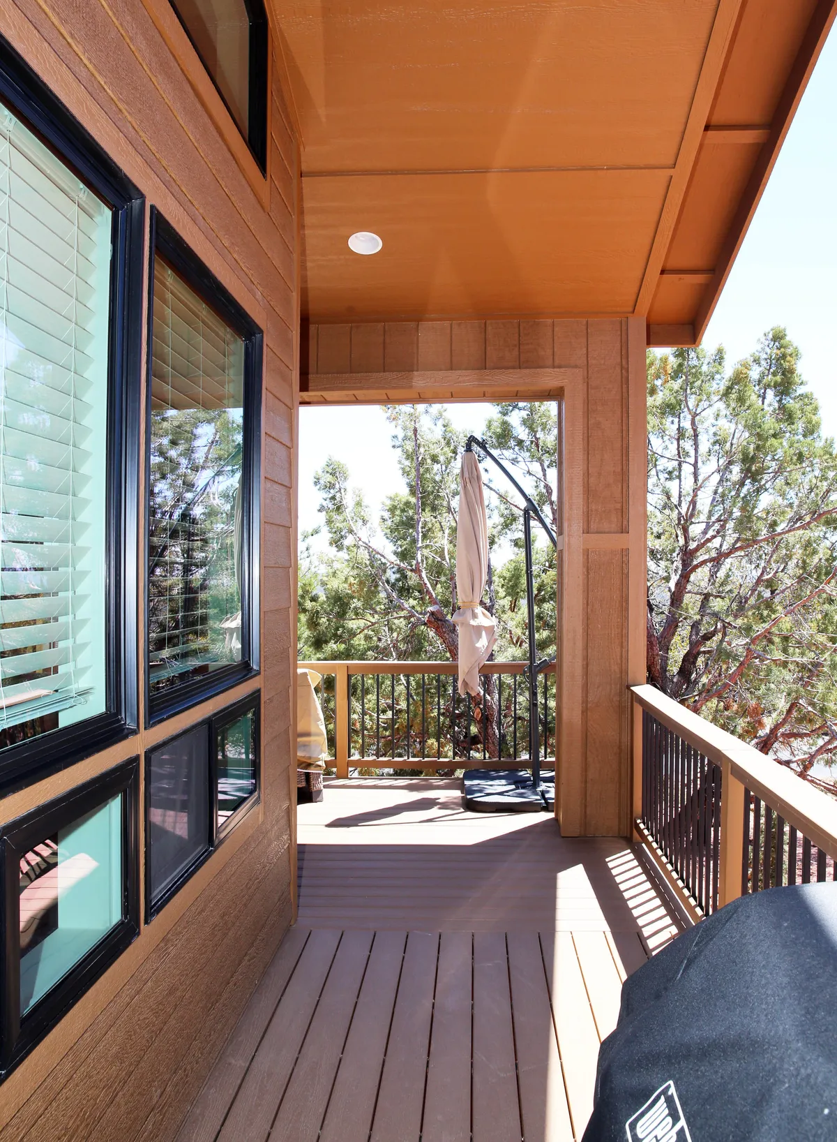 A tranquil outdoor scene featuring a wooden deck with a hanging chair and canopy, surrounded by trees. The setting is peaceful and private, offering a perfect spot for sunrise views or relaxing evenings in nature.