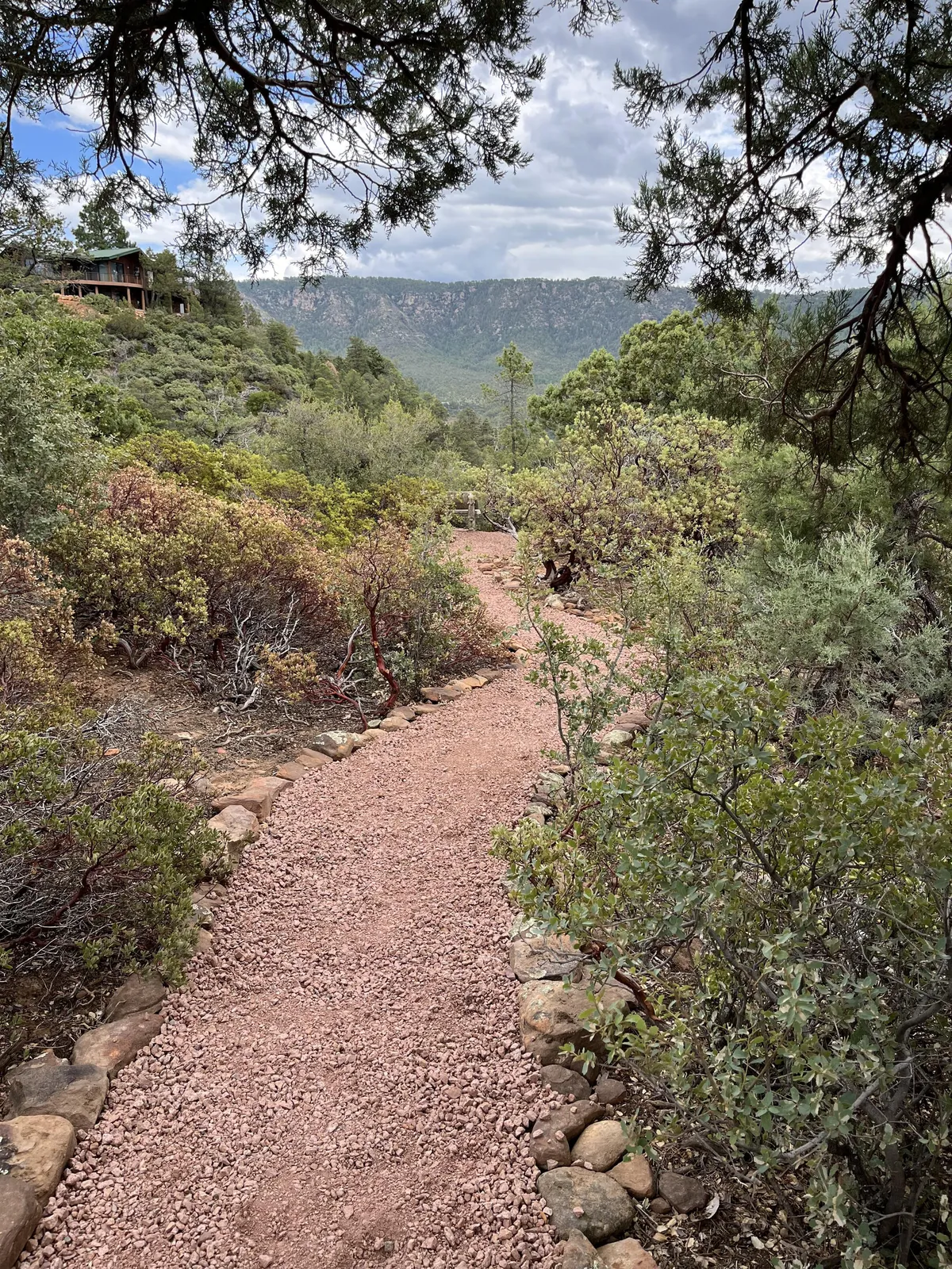 A winding path meanders through lush greenery, leading toward distant mountains and inviting exploration. The scene embodies the spirit of discovery with its peaceful atmosphere, suggesting a private hiking trail that begins right at the property's edge.